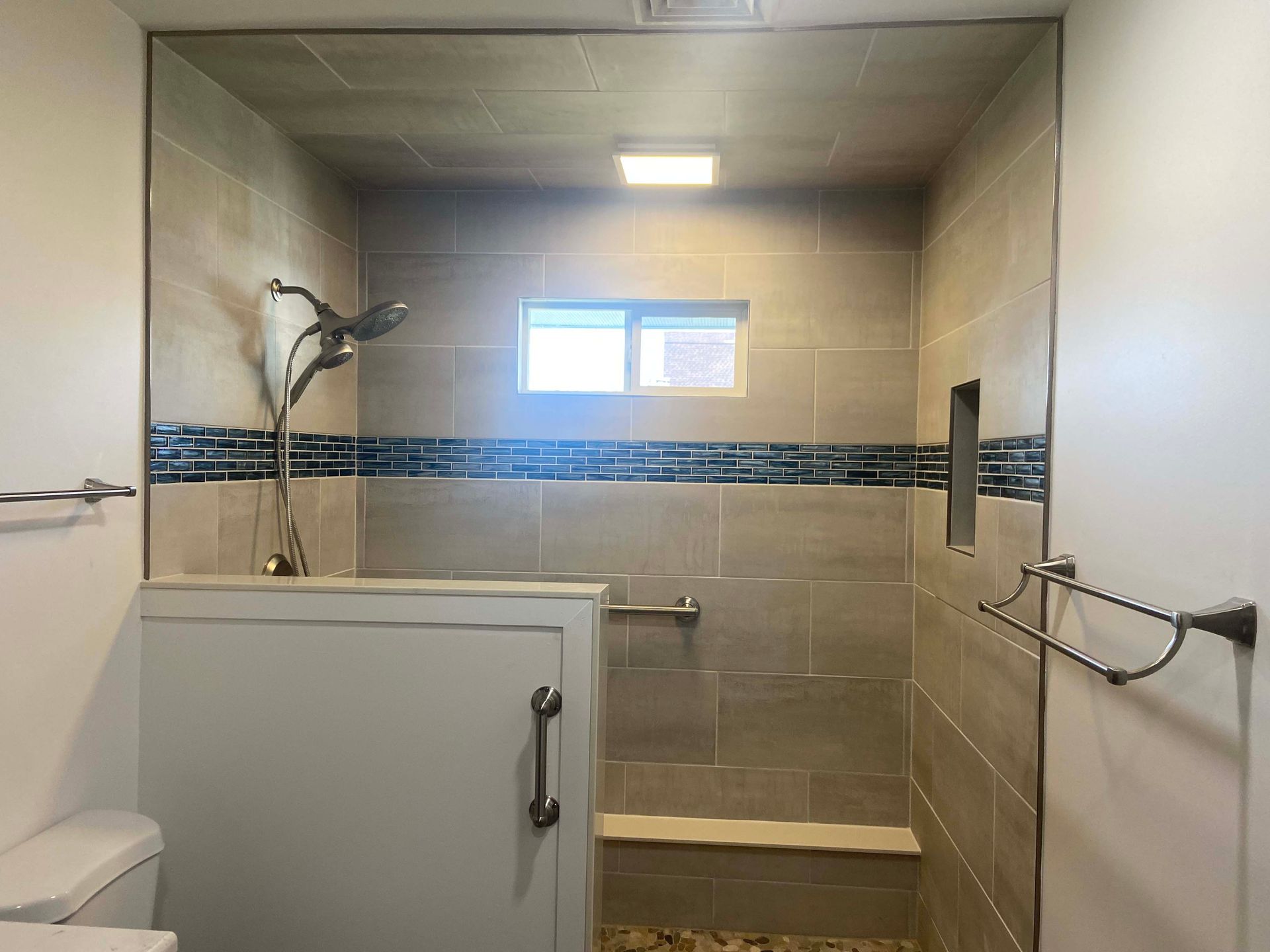 Accessible shower with grab bars, shower bench, and tiled walls in a bathroom