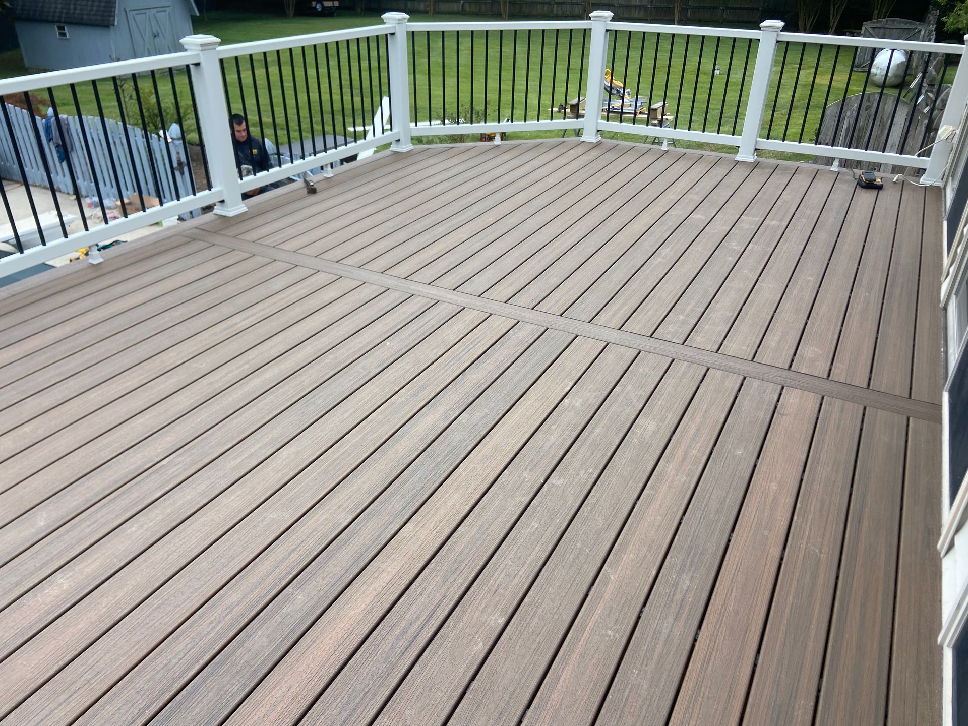 Wooden deck with white railings overlooking a grassy yard and trees