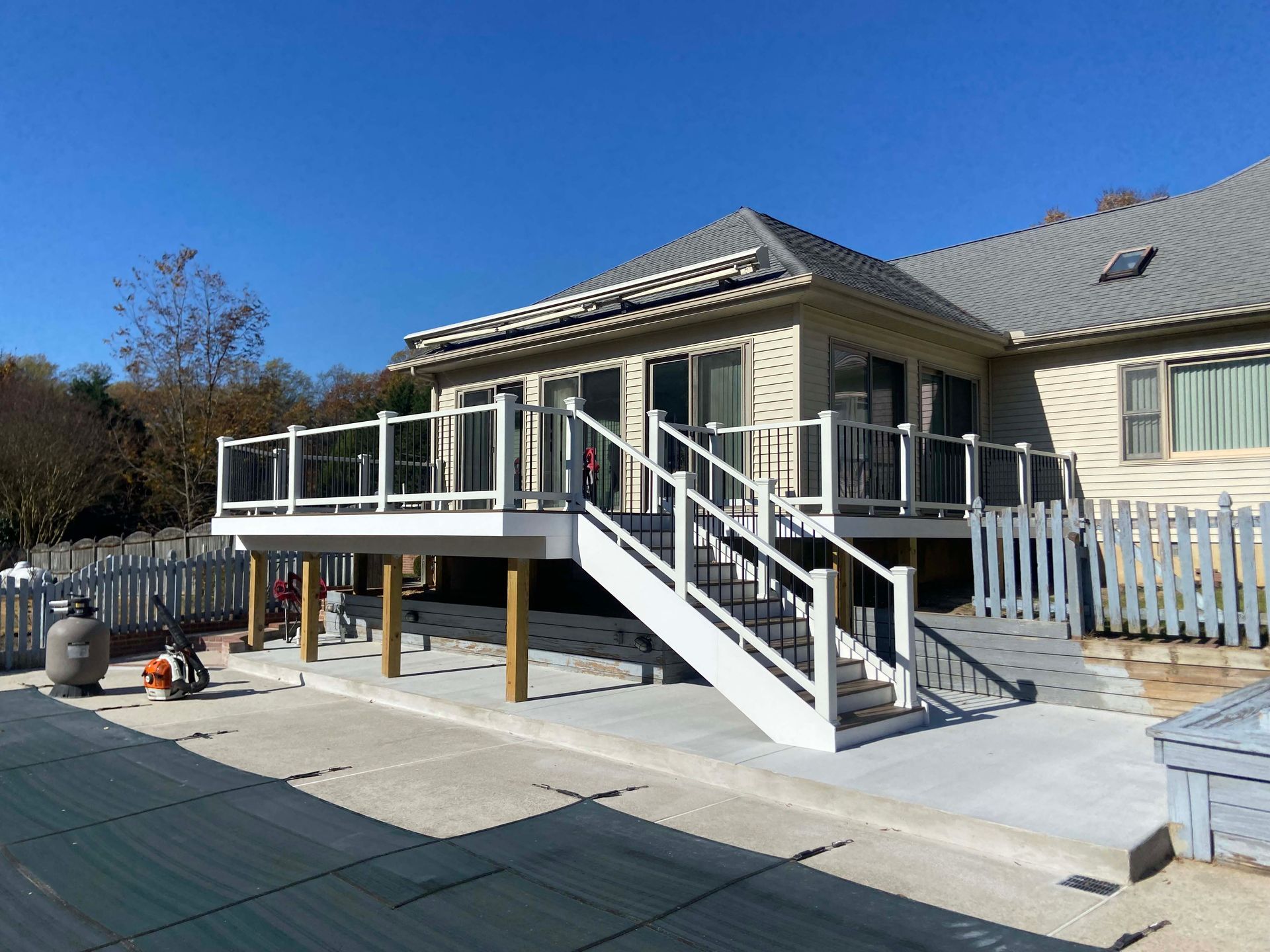 Raised deck and white staircase attached to a beige house on a sunny day