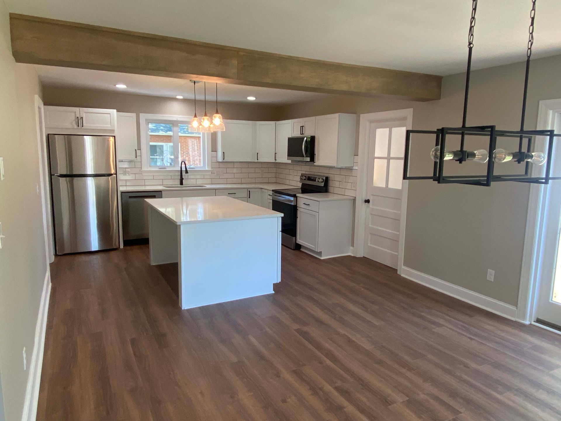 Modern kitchen with stainless steel appliances, white cabinets, island, and wood flooring
