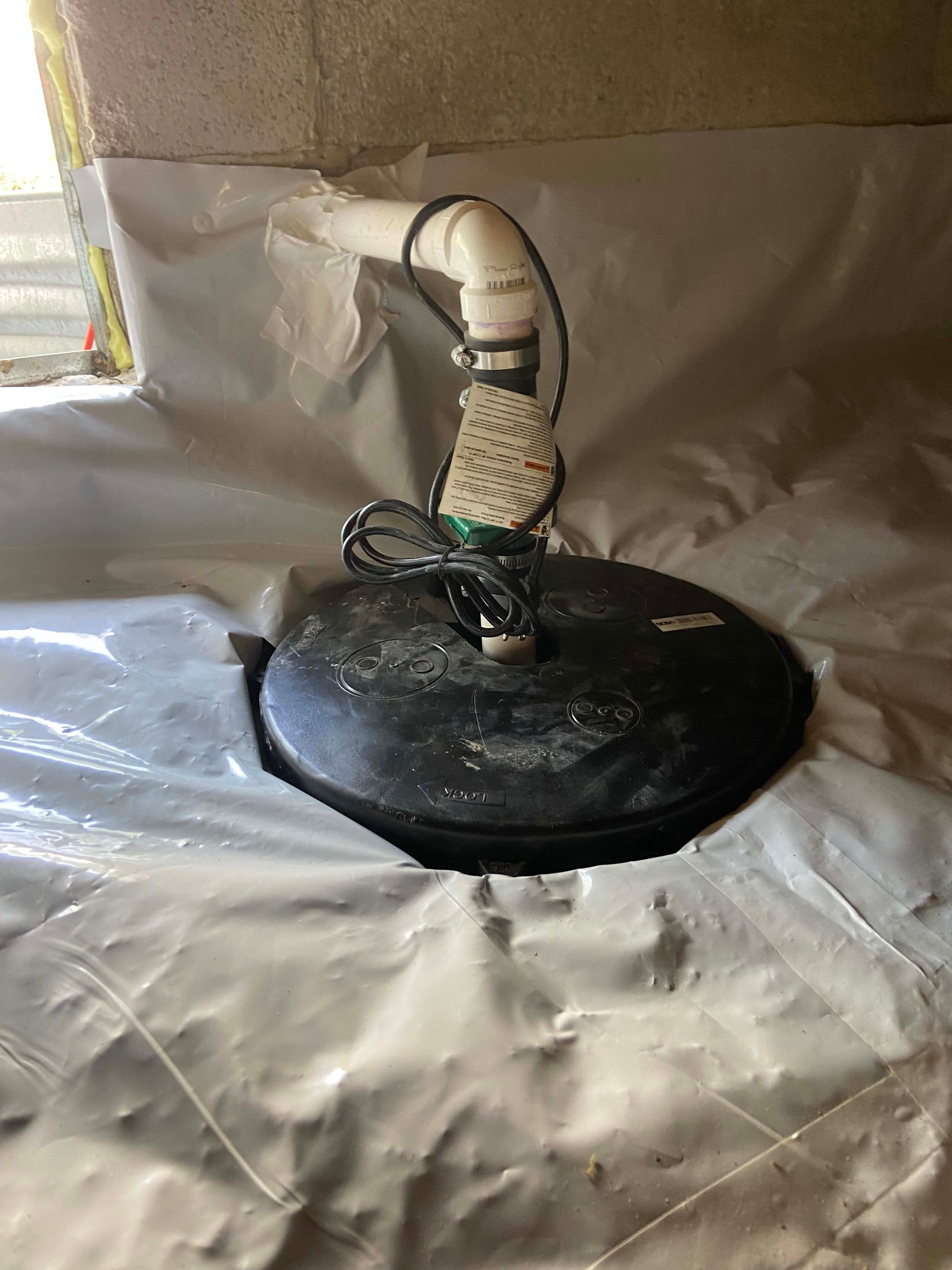 Black dome-shaped sprinkler head with white pipe and wire inside a reflective metal-lined enclosure