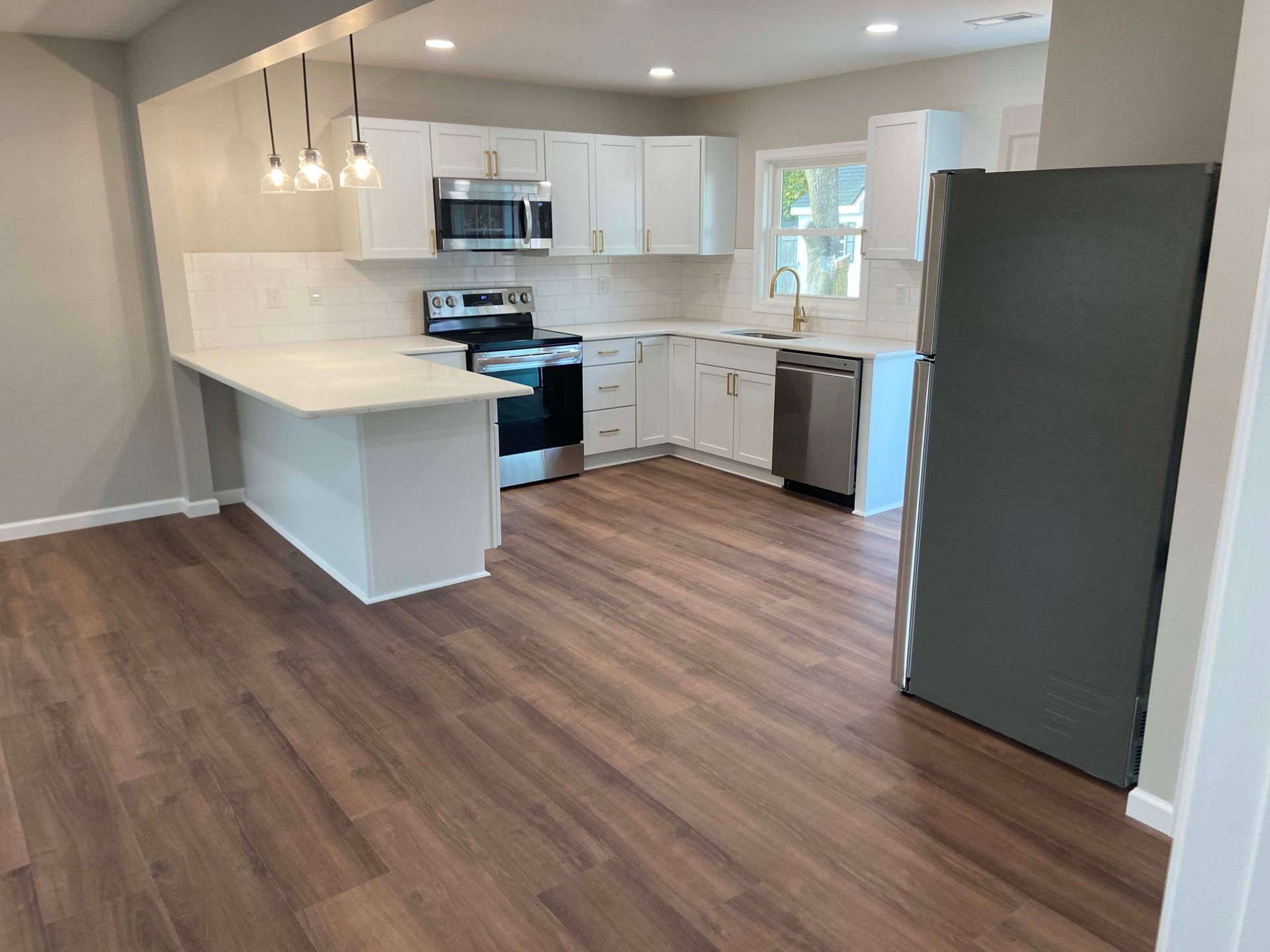 Modern kitchen with white cabinets, stainless appliances, and wood-look flooring