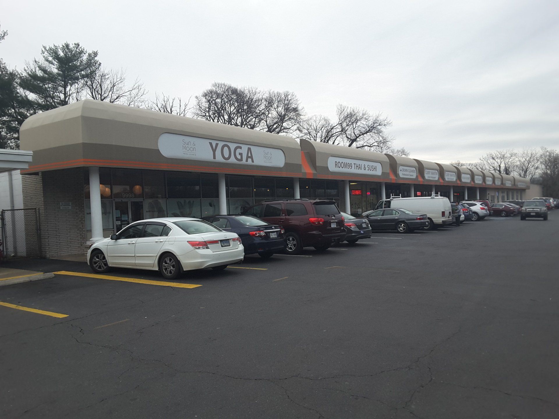 A row of cars are parked in front of a yoga studio.