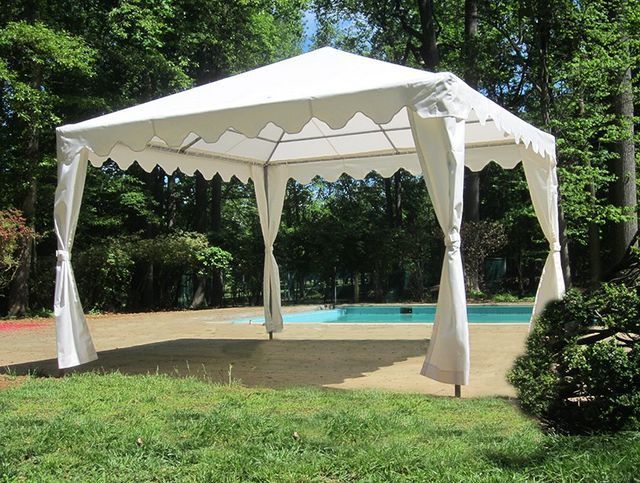 A white tent is sitting in the grass next to a pool.
