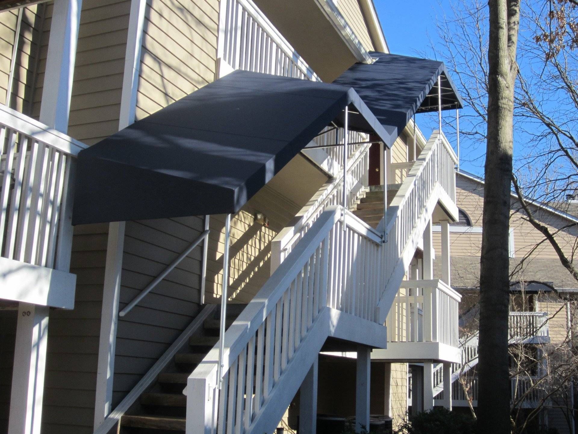 A building with stairs and a black awning over them.