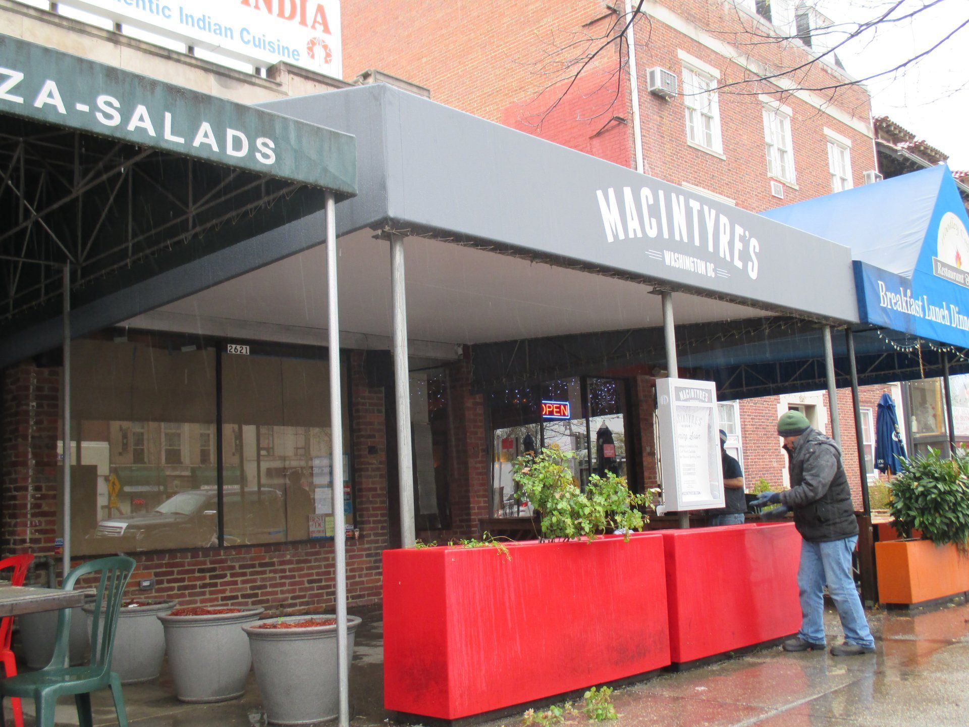 A man standing outside of a restaurant called Macintyre 's.