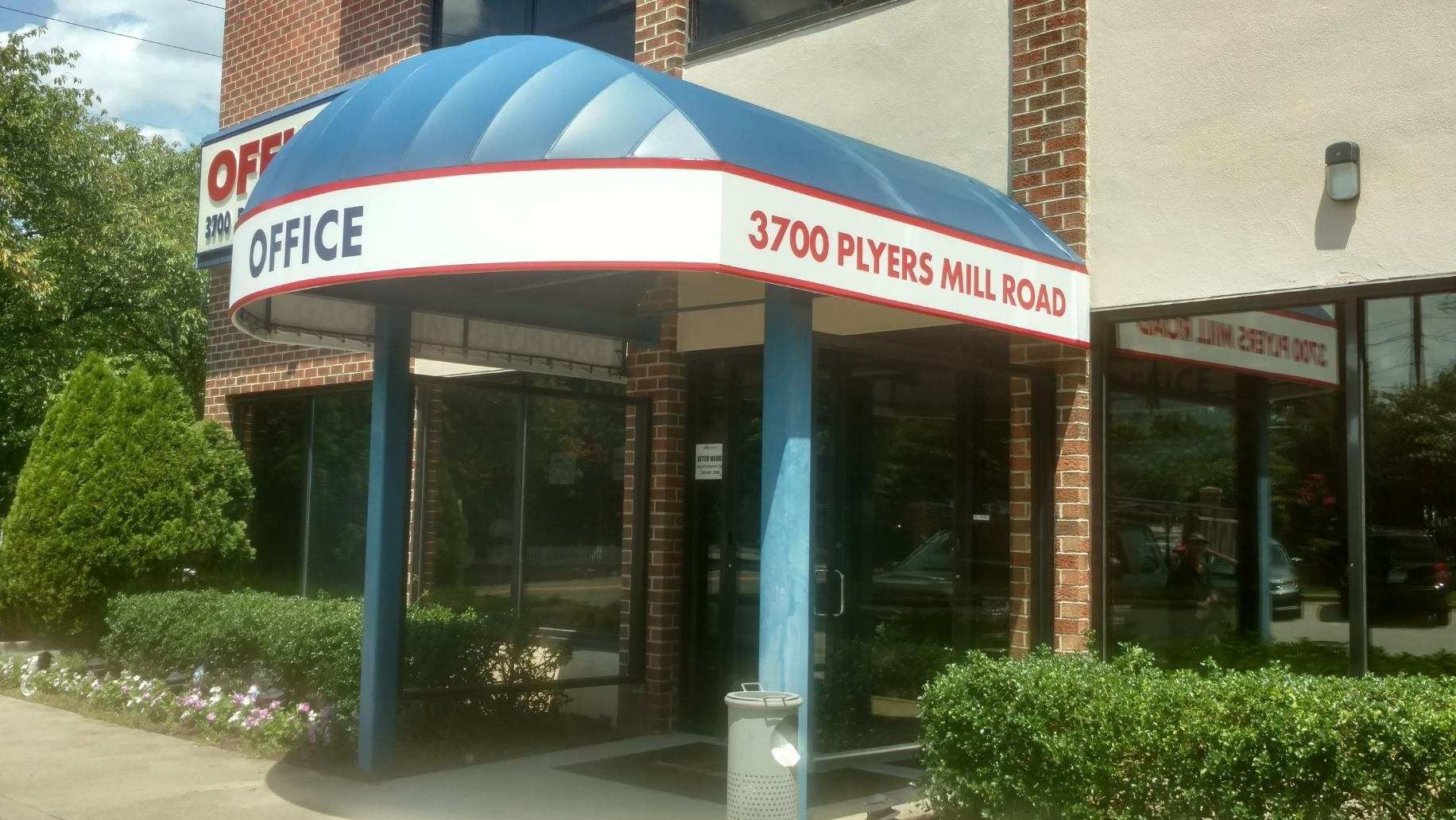 An office building with a blue awning over the entrance.