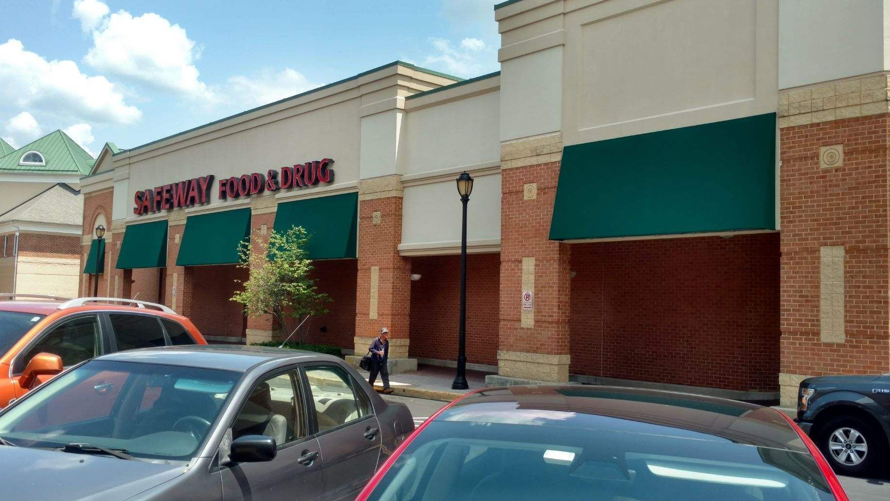 A row of cars are parked in front of a supermarket.