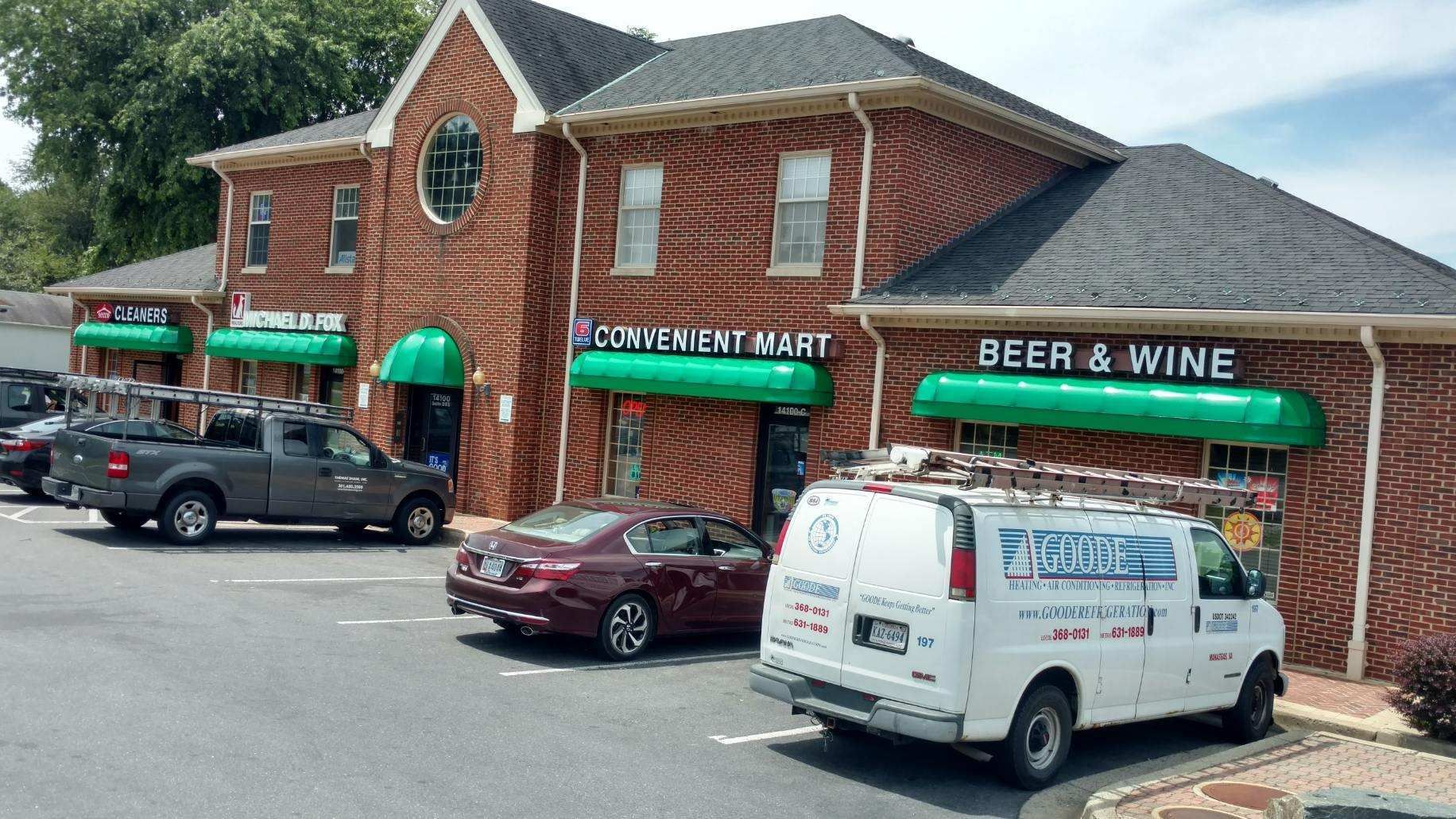 A white van is parked in front of a brick building.
