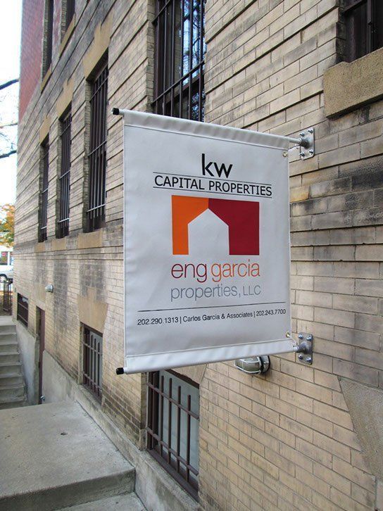 A sign for kw capital properties hangs on the side of a building.