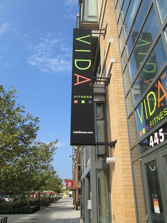 A sign for Vida Fitness hangs from the side of a building.