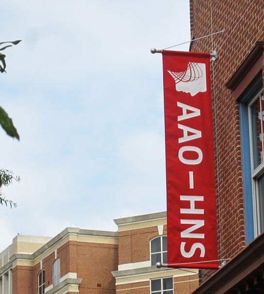 A red banner on a brick building says AAO-HNS.