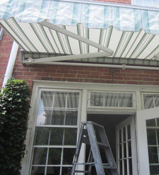 A ladder is sitting under an awning on a brick building.