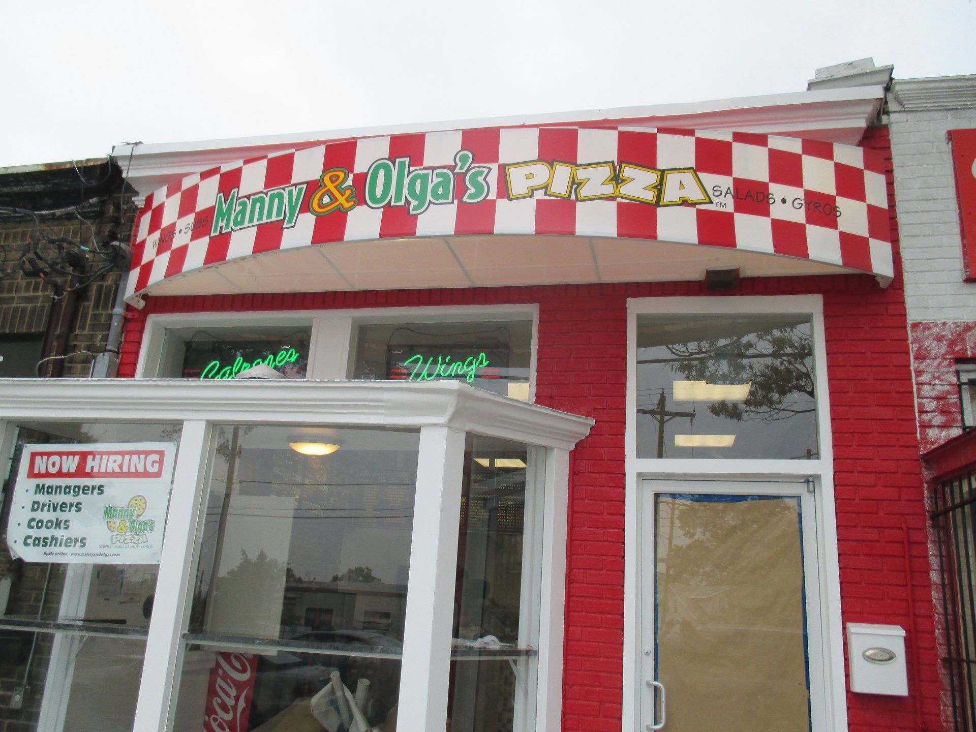 A red and white checkered building with a sign that says Jimmy & Olga 's Pizza.