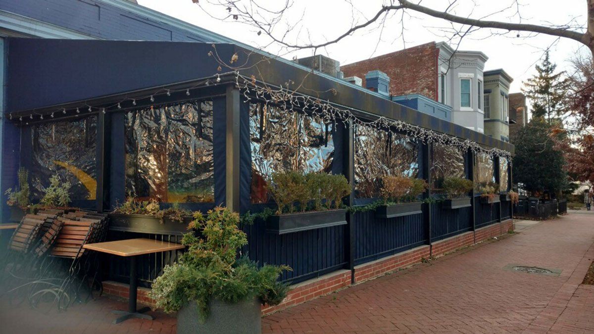 A restaurant with tables and chairs outside on a sidewalk.