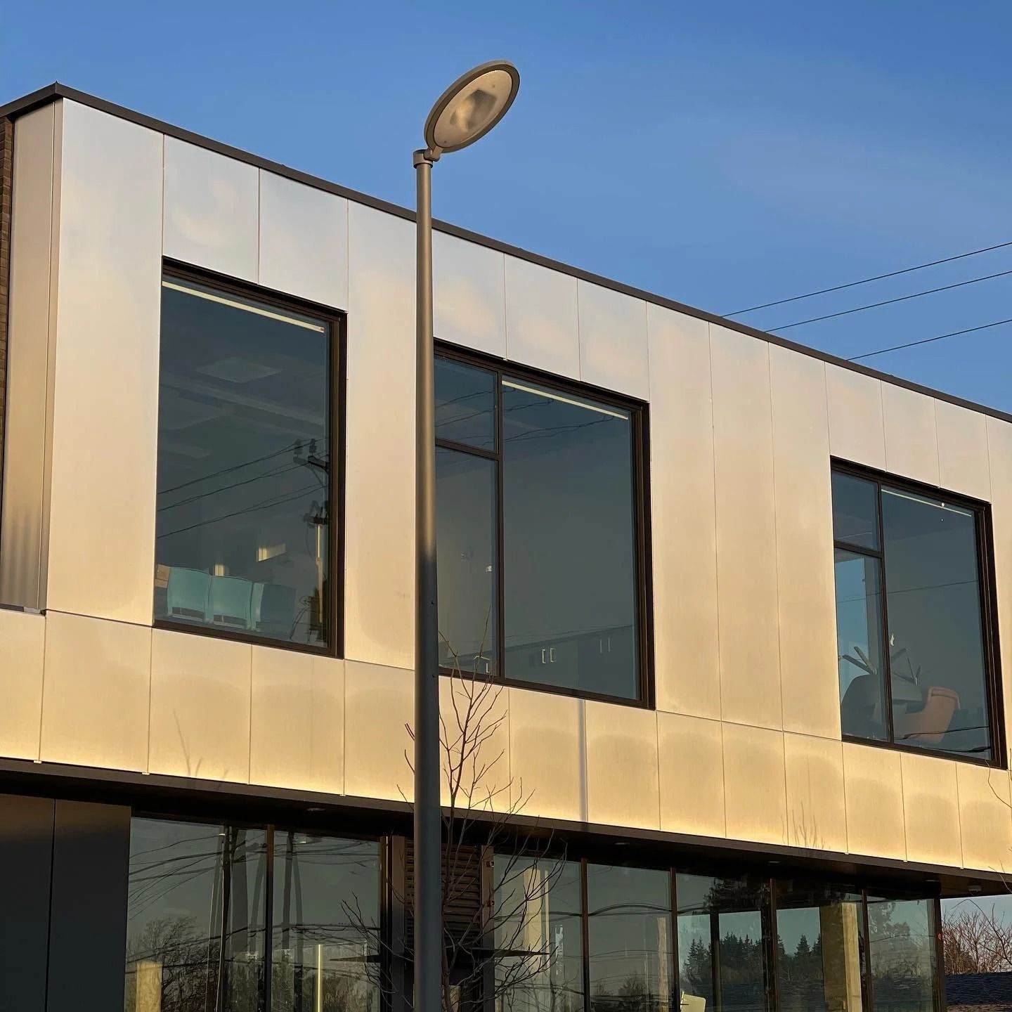 Modern building with reflective metal siding and large windows, a street light in the foreground.