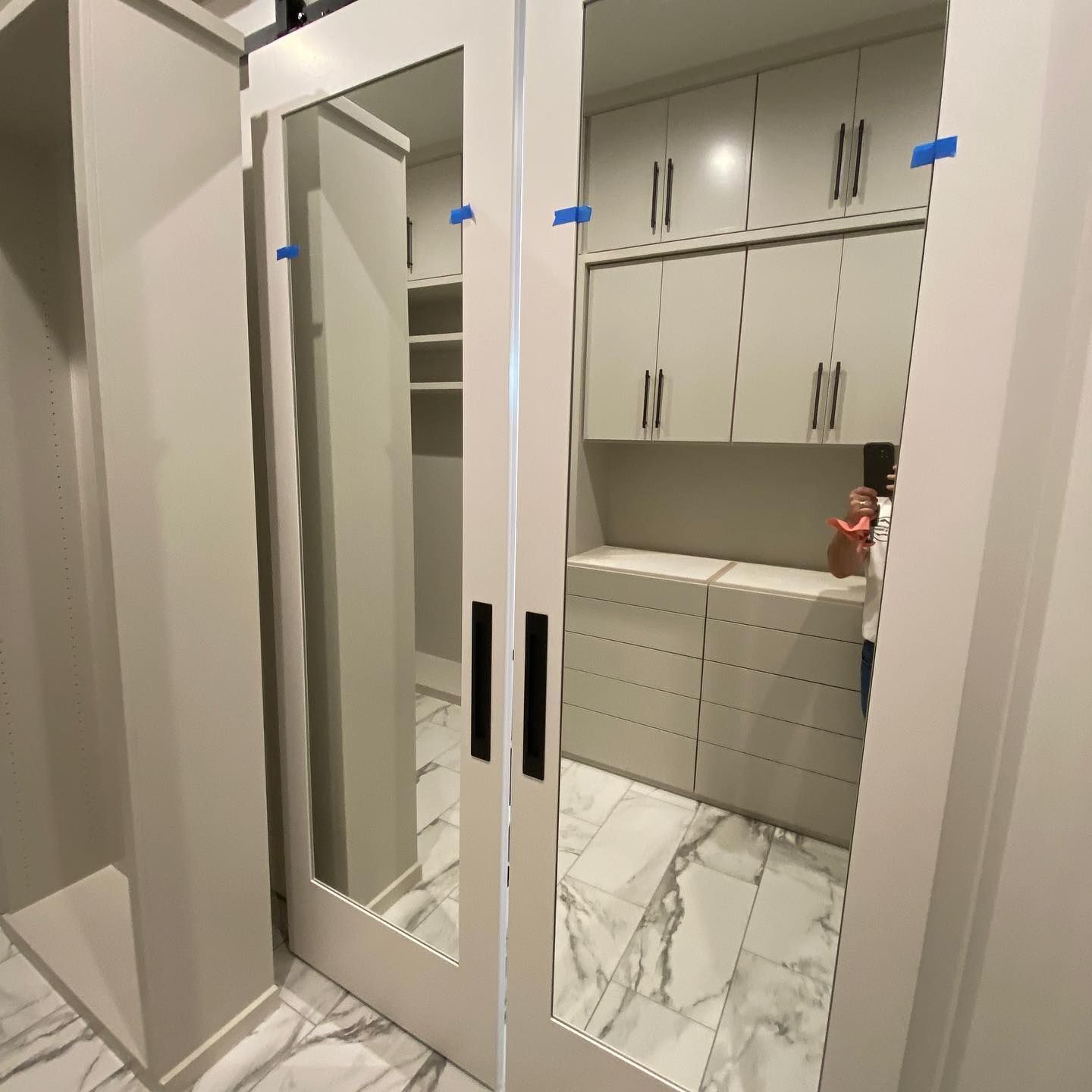 Mirror closet doors open to a built-in closet with cabinets, drawers, and shelving. Marble flooring.