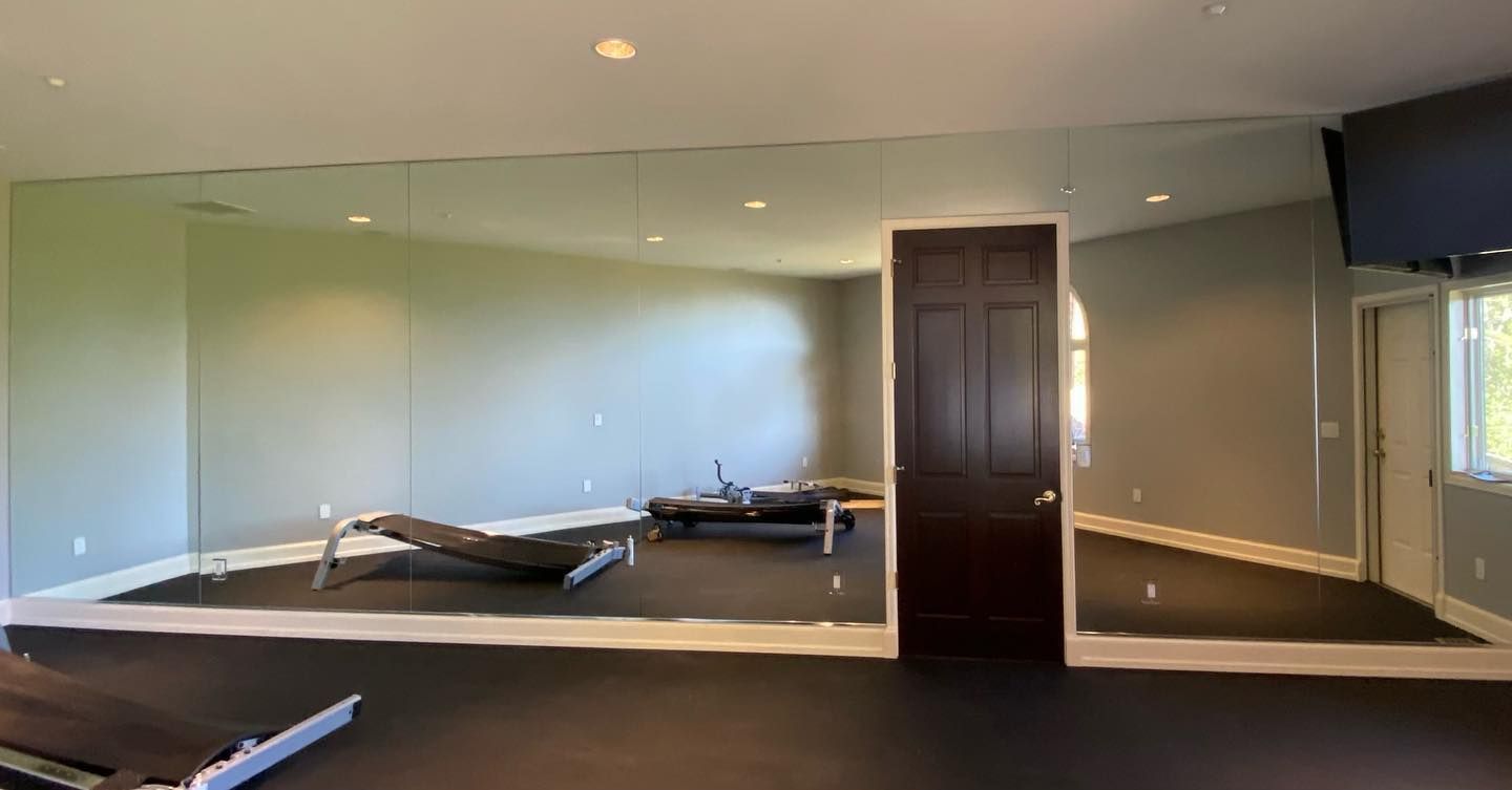 Gym with mirrored wall, exercise equipment on rubber flooring, and a dark brown door.