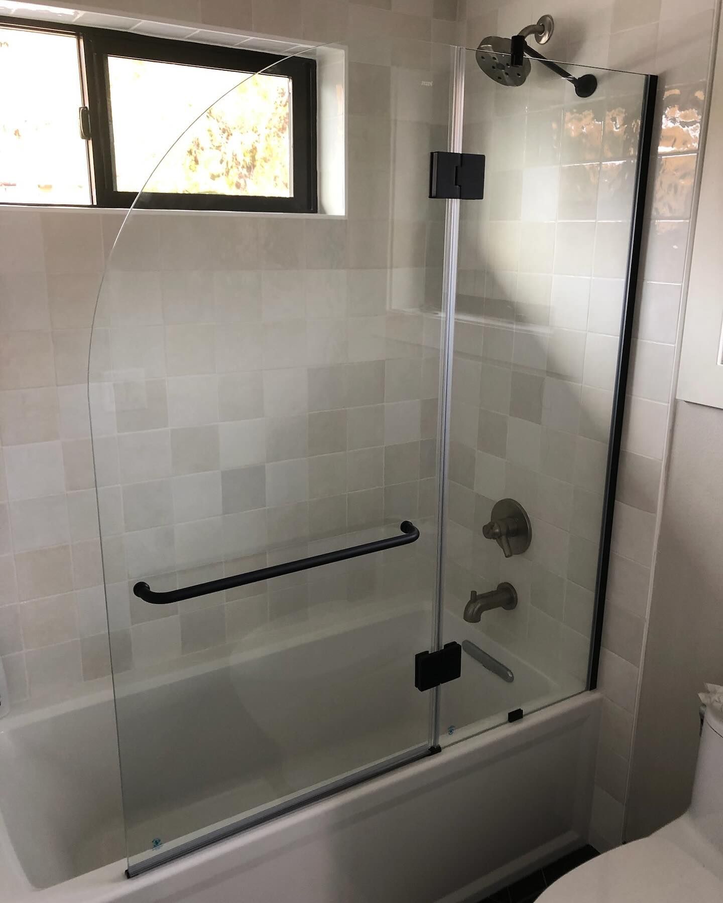 A modern bathroom with a glass shower door and white tile.