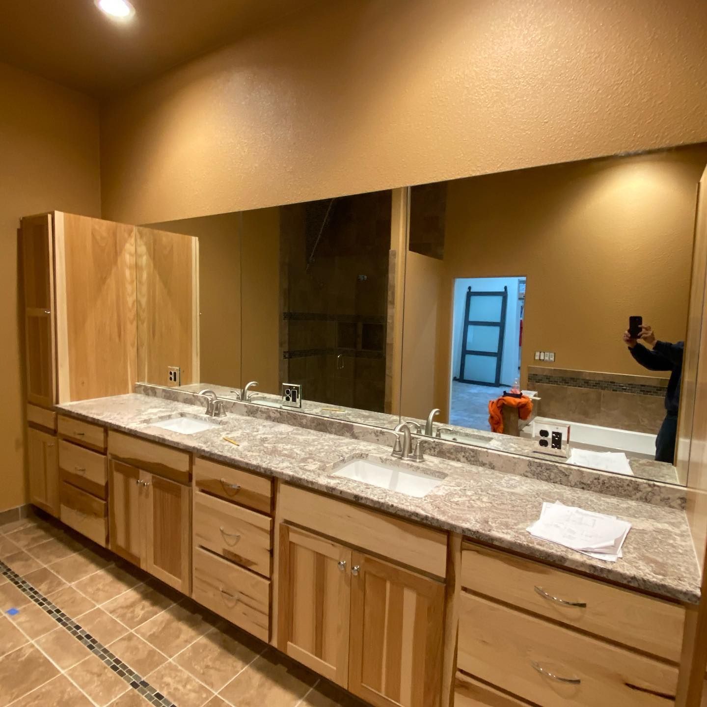 Bathroom with a long vanity, large mirror, and light-colored cabinetry.