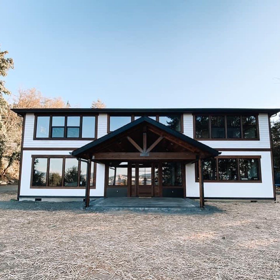 Two-story white house with large windows and a dark wood covered entrance.