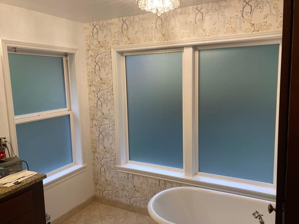 Bathroom with frosted windows, textured wallpaper, and a clawfoot tub.