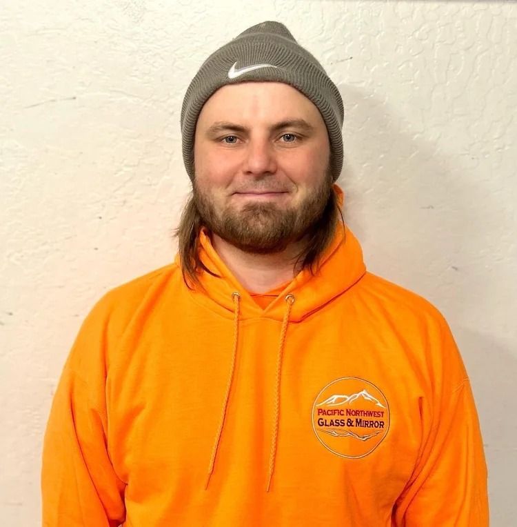 Man wearing a gray beanie and orange hoodie smiles at the camera, with a logo on the hoodie.