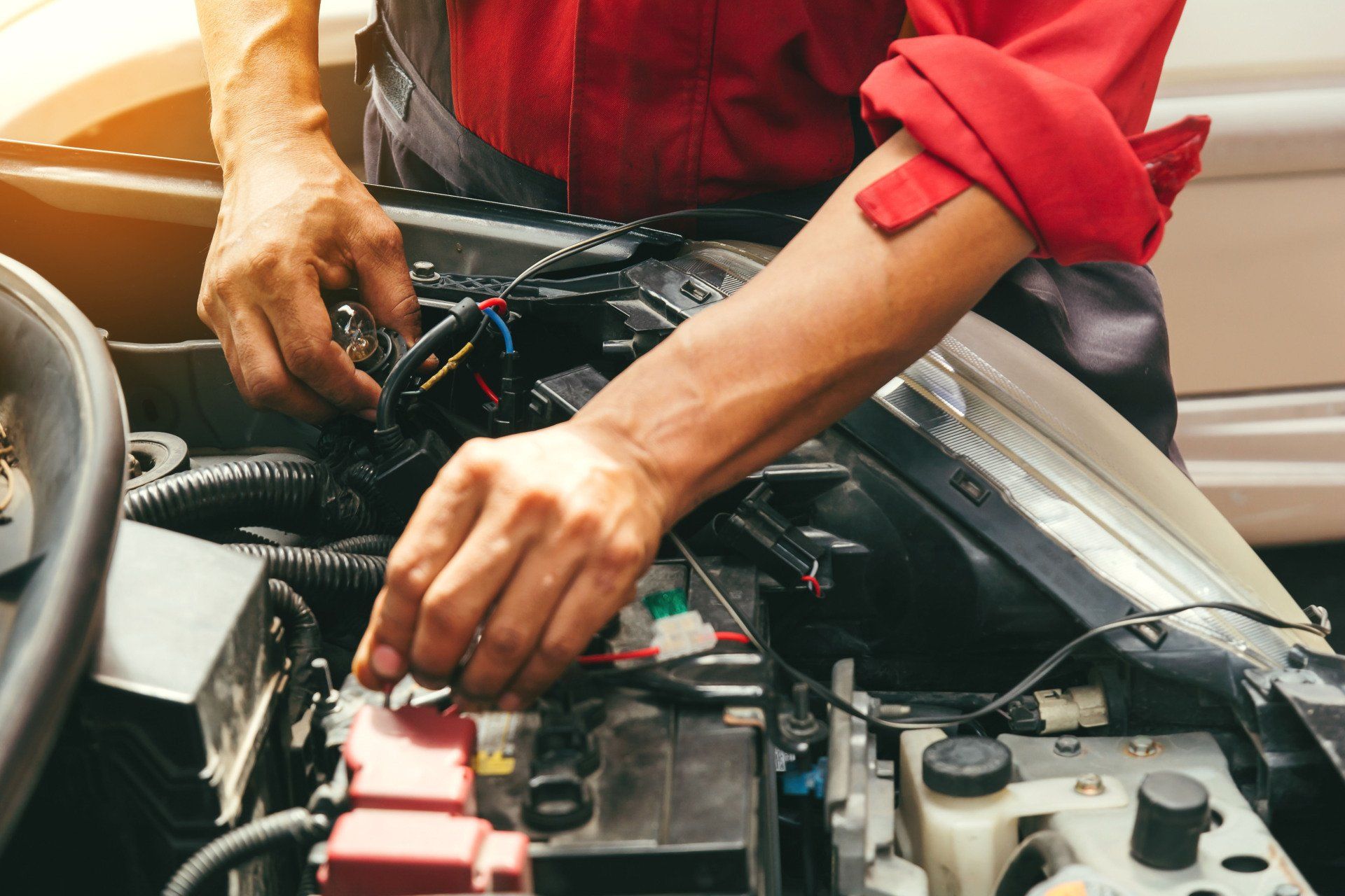 Mechanic working on an open car engine with tools in a garage