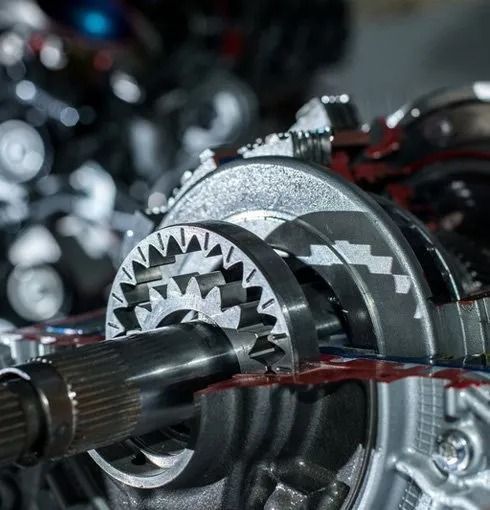 Close-up of a shiny metal gear assembly and shaft inside a mechanical transmission.