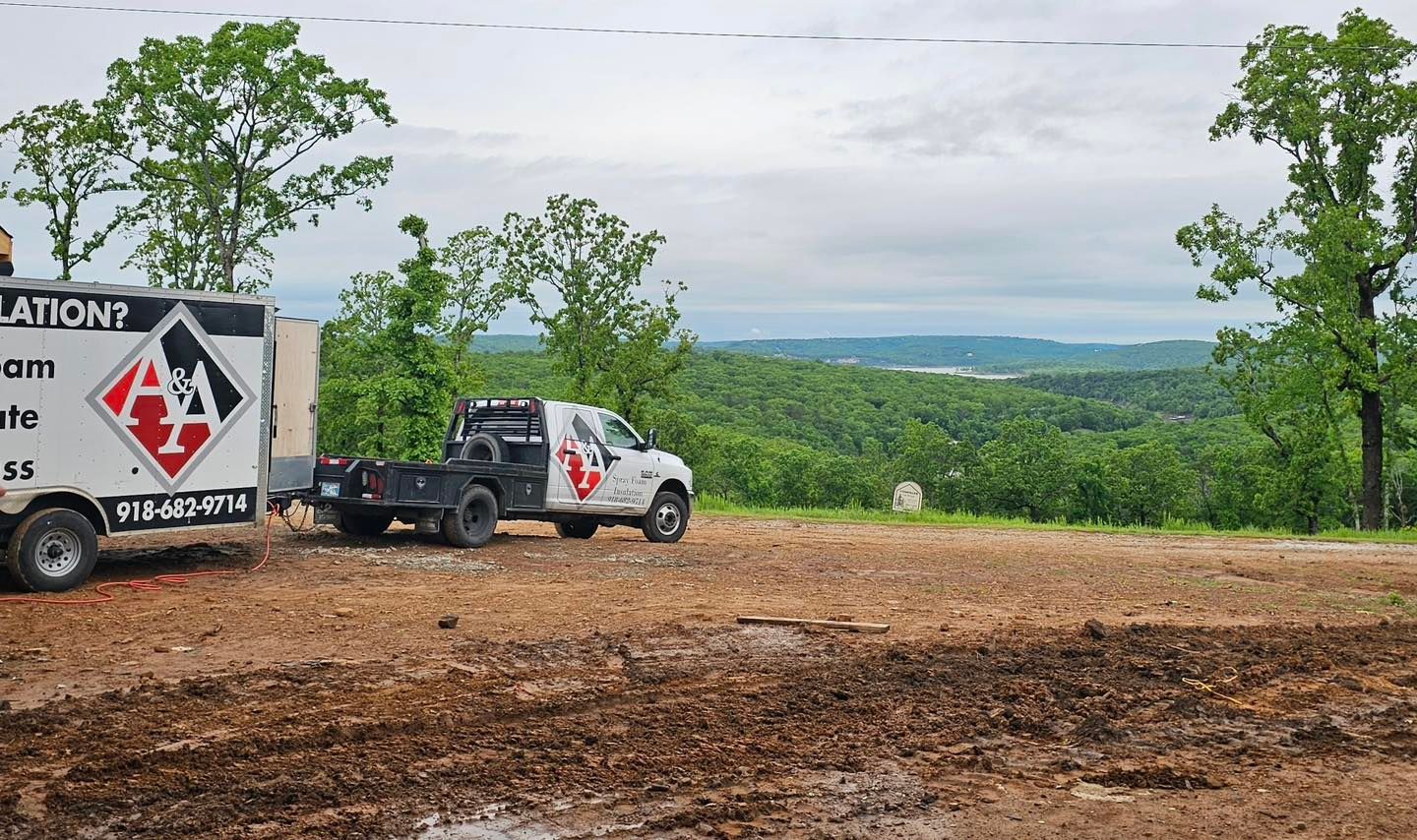 A white work truck and trailer on a muddy site overlooking a tree-filled valley.