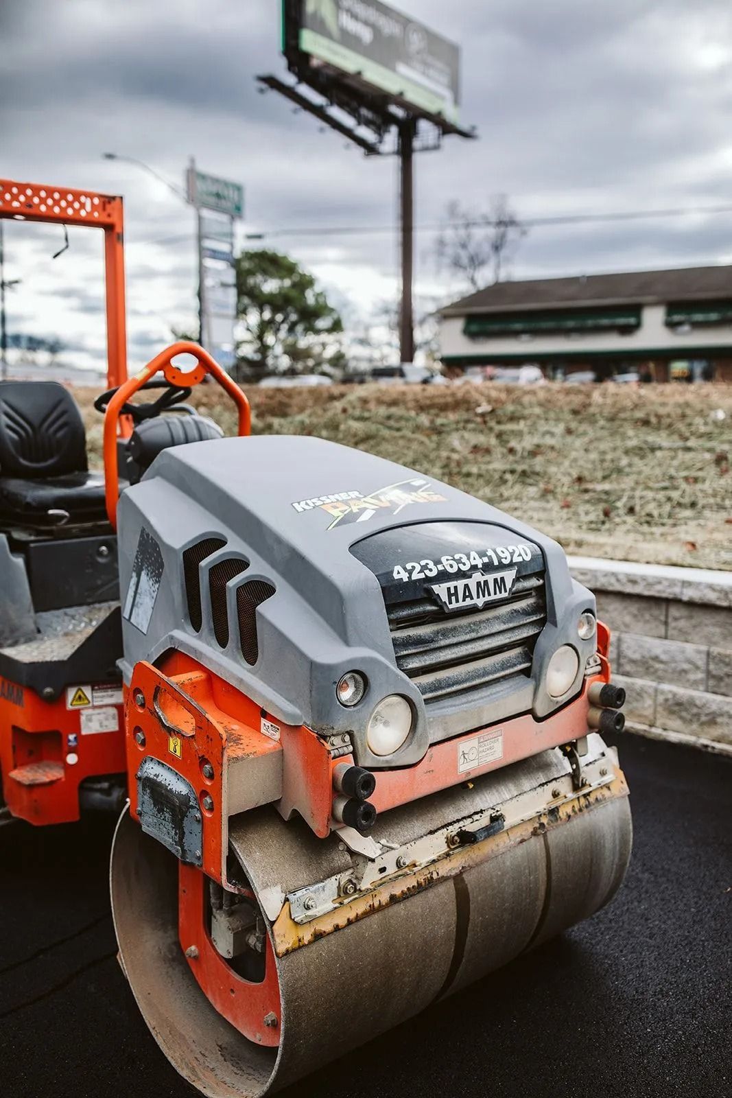 A compact asphalt roller machine smoothing a freshly paved road.