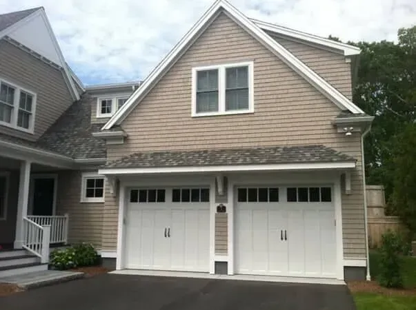 Two-story beige house with white double garage doors and a small front porch