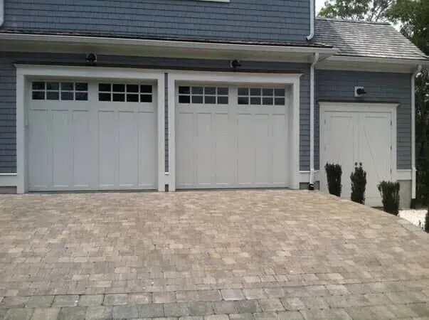 Suburban house with two white garage doors, a side door, and a paved driveway