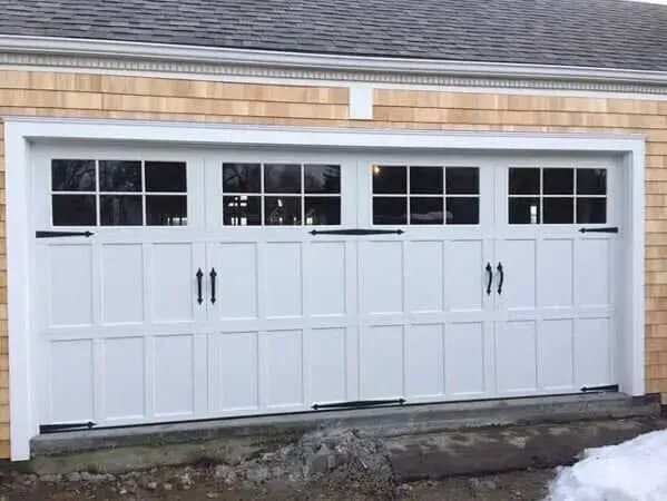 White four-car garage doors with windows on a house exterior, viewed from the driveway