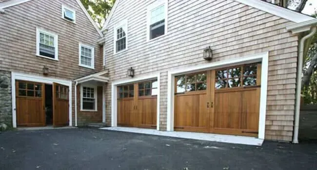 Two-car garage with wood doors and beige siding in a residential driveway