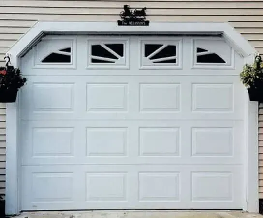 White garage door with four small windows, set in a light-sided house exterior