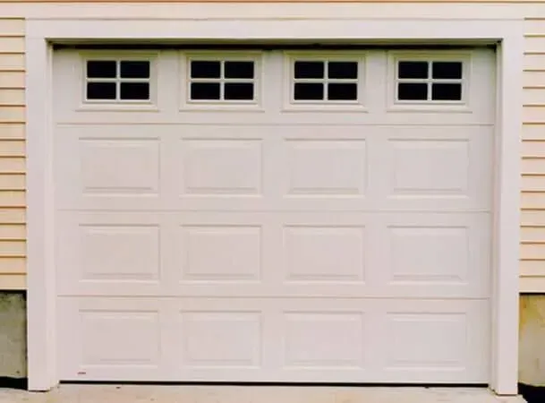 White double garage door with four small windows at the top, set in beige siding.