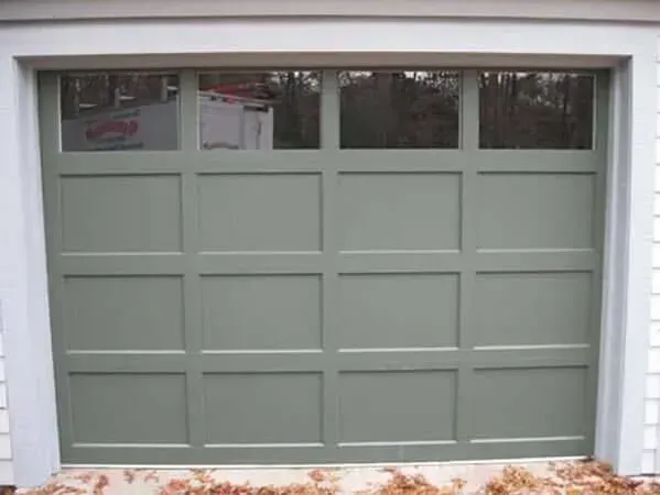 Light green paneled garage door with four small windows at the top