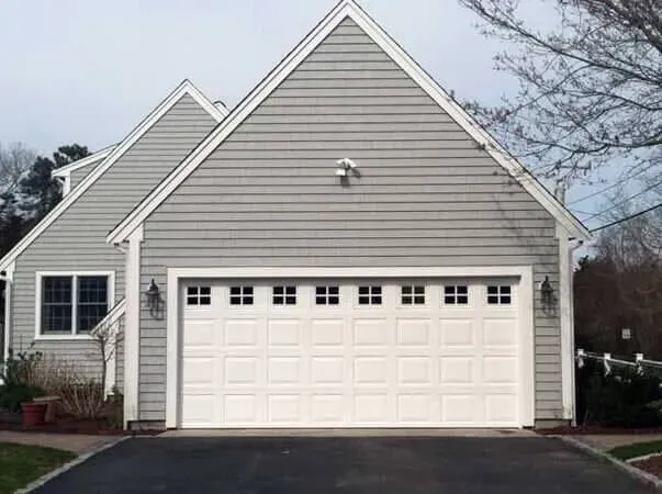 Suburban house with a double garage, white siding, and a dark roof