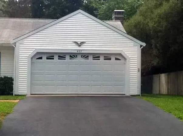 White two-car garage with a closed door and asphalt driveway in a suburban setting