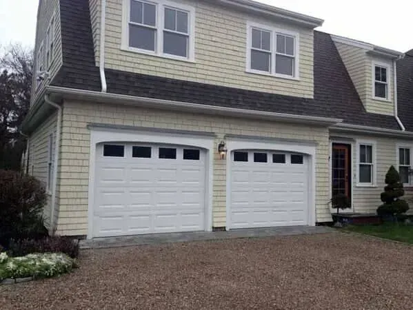 Suburban house with two white garage doors and a gravel driveway