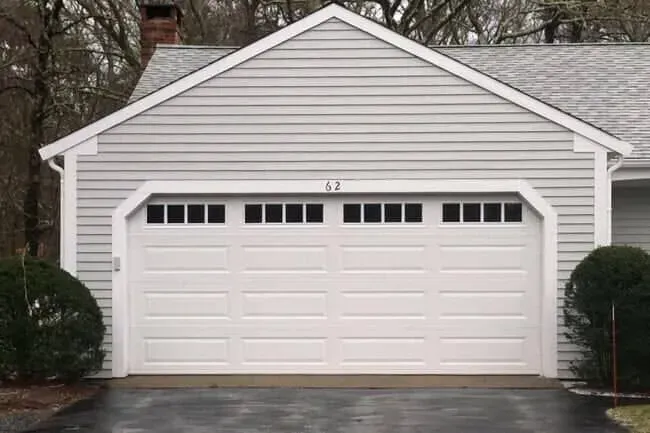 White two-car garage with a double door and small windows, set in a suburban house exterior.