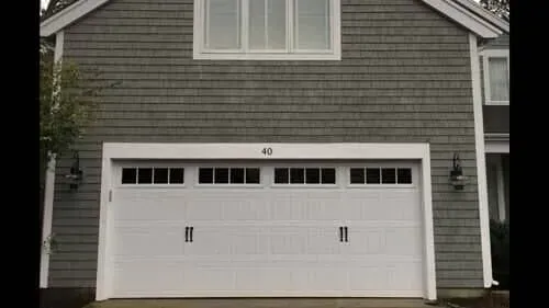 Gray house facade with a white double garage door and small windows at the top.