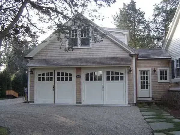 White double garage doors on a suburban house with a gravel driveway and stone walkway