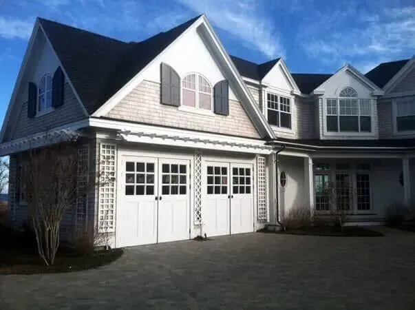 Large white house with dormer windows and a double garage under a blue sky