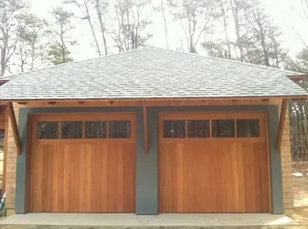 Modern wooden double garage with gray roof and central pillar, viewed front-on outdoors
