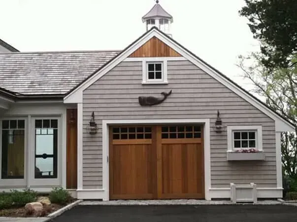 Gray house with double wooden garage doors and a small cupola above the gable