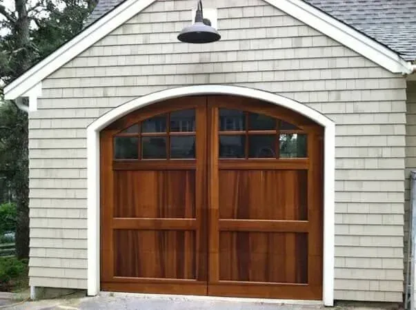Gray garage with arched wooden double doors and a black light above the entrance