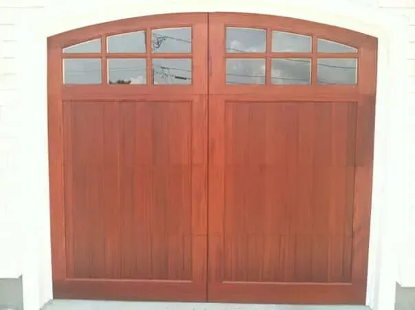 Wooden double front door with arched glass panes above and red-brown panels