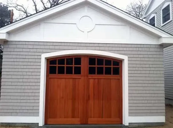 Gray garage with white trim and a wooden double door, centered under a gable roof.
